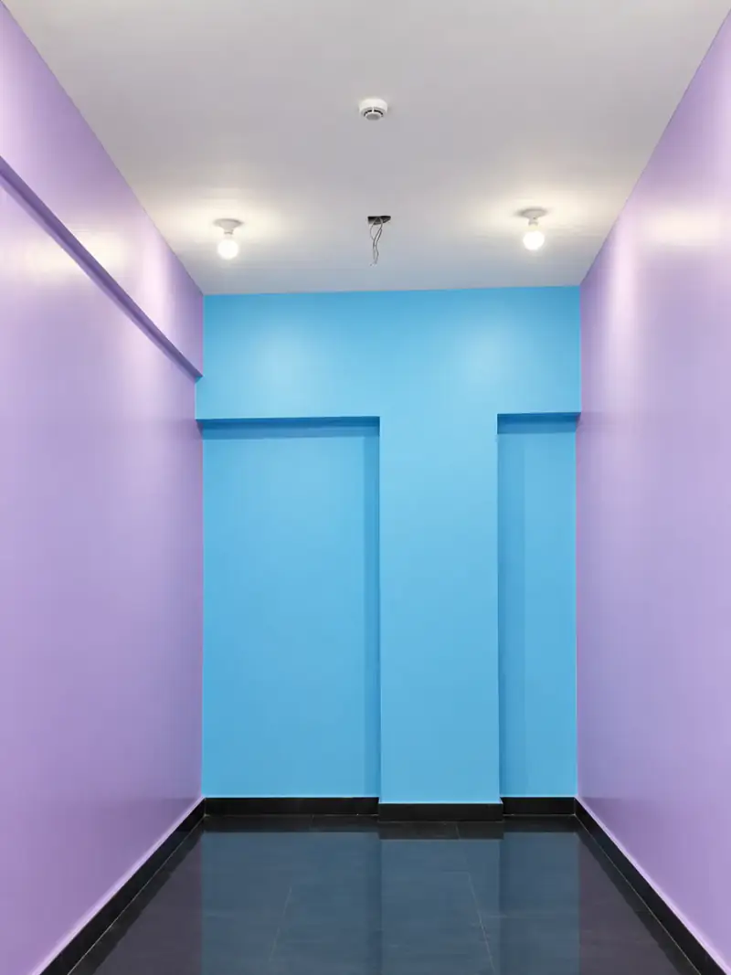 Apartment corridor painted lavender with a blue end wall and cove lighting