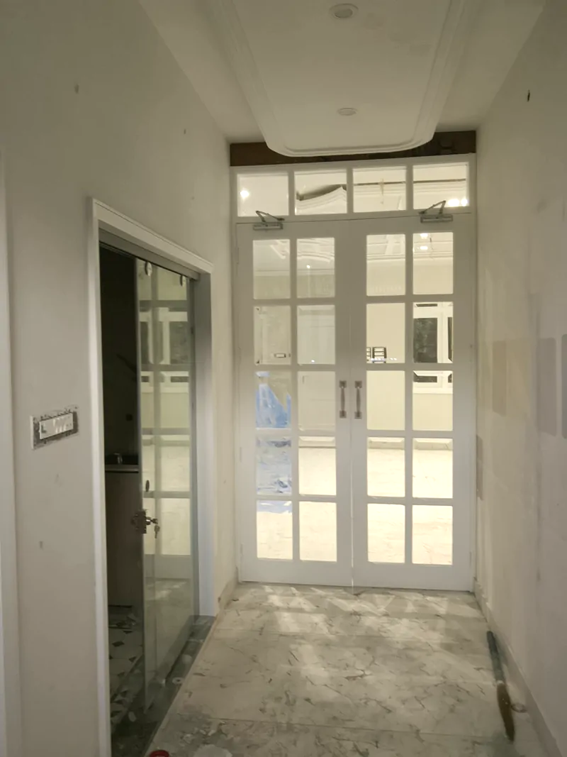 White glazed double doors with a fanlight above, seen from an internal lobby with a marble floor