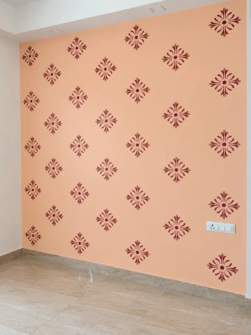 Salmon wall with a hand-stencilled maroon damask motif repeating in even rows